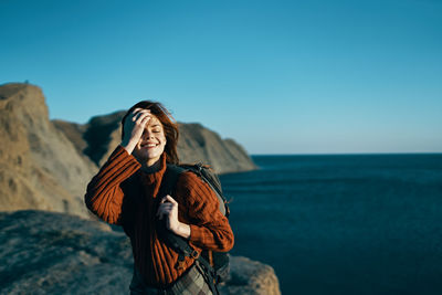 Young woman standing on rock against sea