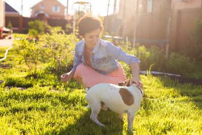 Young woman playing with dog on field