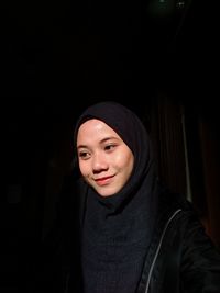 Portrait of beautiful young woman against black background