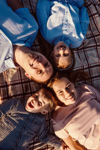 High angle portrait of smiling family lying on blanket in park