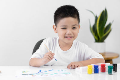 Portrait of smiling boy holding table at home