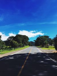 Road amidst trees against blue sky