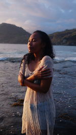 Woman looking away at sea shore against sky