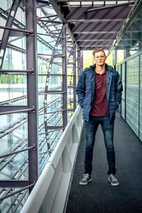 Portrait of young man standing against railing