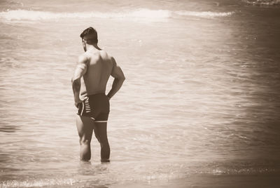 Shirtless muscular man standing in sea