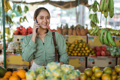 Portrait of young woman holding fruits at market