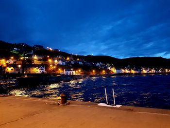 Illuminated city by buildings against sky at night