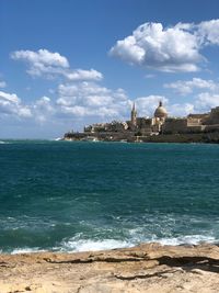 Buildings by sea against sky