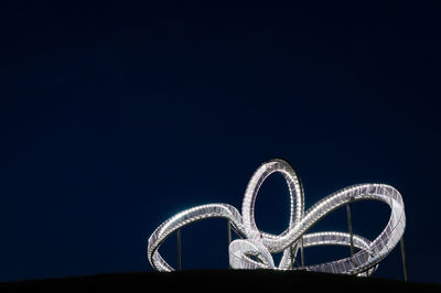 Low angle view of illuminated ferris wheel against sky at night