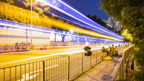 People on illuminated bridge in city at night