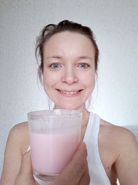 Portrait of smiling woman holding drink standing at home