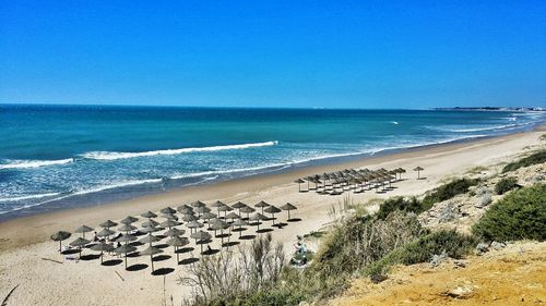 Scenic view of beach against clear blue sky