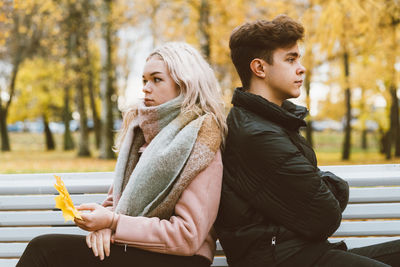 Angry young couple sitting in park