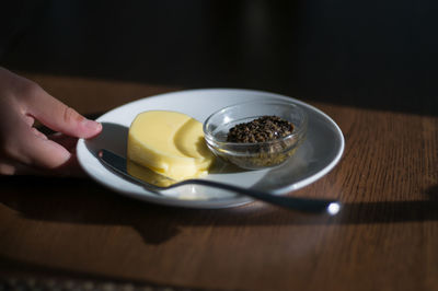 Cropped hand holding plate with food on table