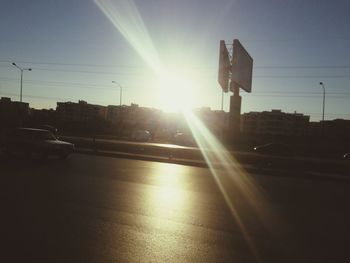 Cars on city street against sky during sunset