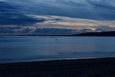 View of calm beach against cloudy sky