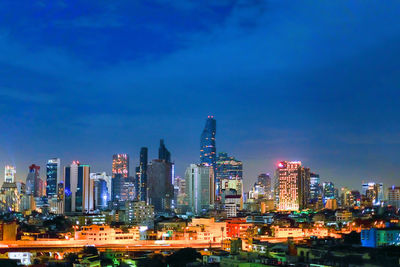 Illuminated buildings against blue sky at night