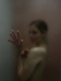 Naked young woman in bathroom seen through window