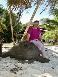 Portrait of woman standing by palm tree