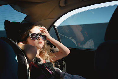 Girl in sunglasses sitting in car
