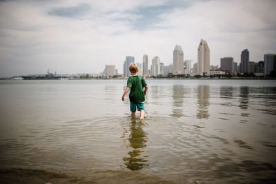 Six year old boy wading into coronado bay san diego skyline