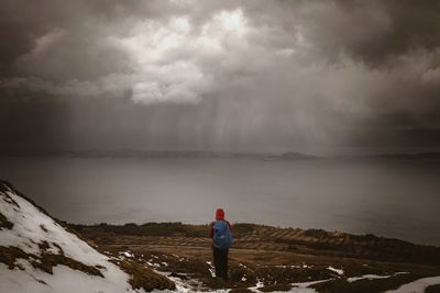 Man standing on landscape against cloudy sky