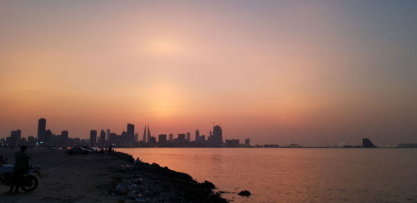 Panoramic view of sea and buildings against sky during sunset