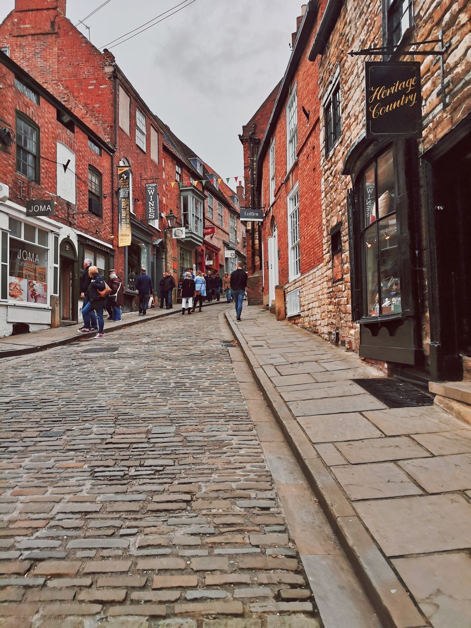 PEOPLE WALKING ON STREET AMIDST BUILDINGS