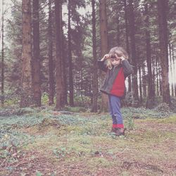 Full length of girl standing against trees in forest