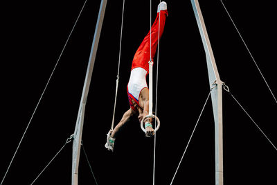Low angle view of man performing acrobat against black background