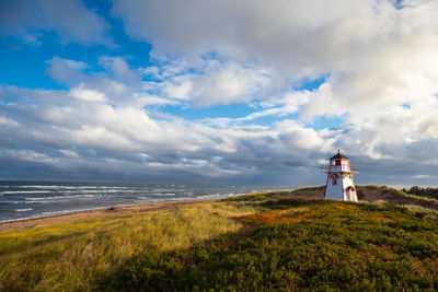 Lighthouse by sea against sky