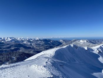 Aerial view of snowcapped mountains against clear blue sky