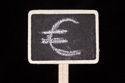 Close-up of road sign against black background