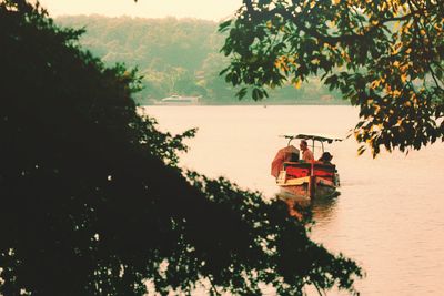 People sitting on boat against trees