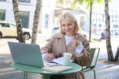 Young woman using laptop at cafe