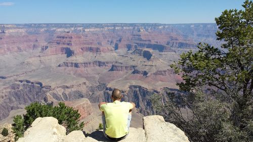 Rear view of woman by rocky mountains against clear sky