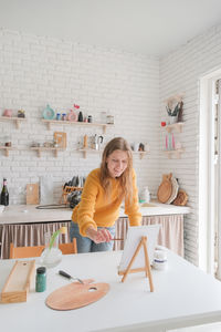 Portrait of young woman using mobile phone while sitting at home