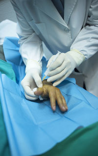 Close-up of doctor injecting syringe in patient hand in operating room