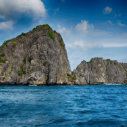 Rock formations by sea against blue sky