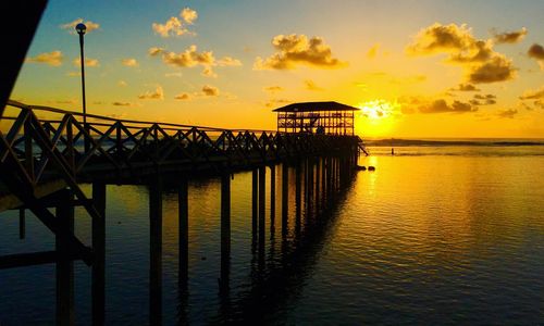 Pier over sea against sky during sunset