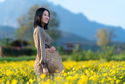 Young woman with yellow flower on field