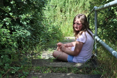 Side view of teenage girl sitting on field