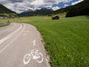 Road amidst field and mountains against sky