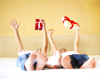 Cute girls holding christmas gift box while lying on bed