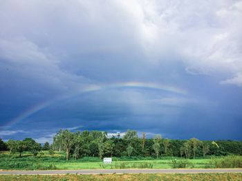 Scenic view of field against rainbow in sky