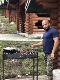 Portrait of man showing thumbs up by food on barbecue grill