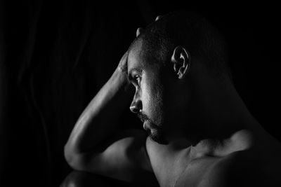 Portrait of shirtless man against black background