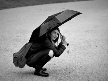 Portrait of young woman holding umbrella on land