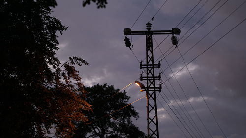 Low angle view of silhouette electricity pylon against sky at sunset