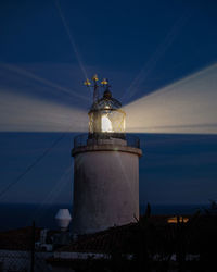 Lighthouse by sea against sky at dusk